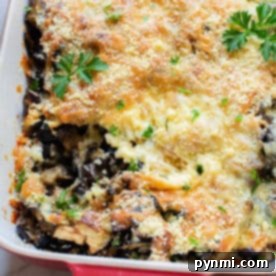 Baked vegetarian casserole topped with melted cheese, breadcrumbs, and parsley in a red baking dish—a delicious eggplant recipe perfect for any meal.