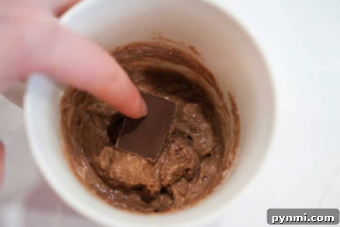 Lava Cake Bliss: Single-Serving Indulgence 4 Preparing a lava cake in a mug by pressing chocolate into the batter.