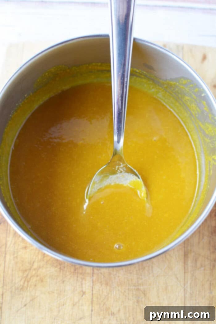A bowl of yellow-orange Bologna Burnt Ends sauce.