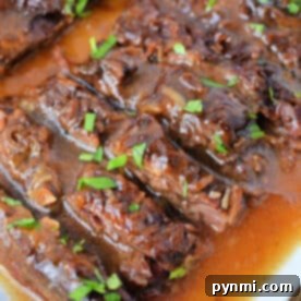 Sliced Slow Cooker Skirt Steak in rich brown gravy, garnished with chopped fresh parsley on a white serving platter.