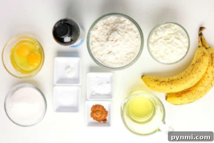 Power-Packed Banana Bread 3 Top view of baking ingredients for Protein Banana Bread: eggs, flour, sugar, oil, bananas, vanilla, cinnamon, and small bowls with powders.