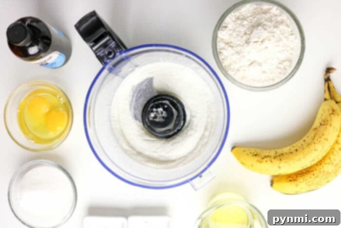 Power-Packed Banana Bread 4 Top view of Protein Banana Bread ingredients: flour, eggs, bananas, sugar, oil, vanilla, and a food processor with flour inside.