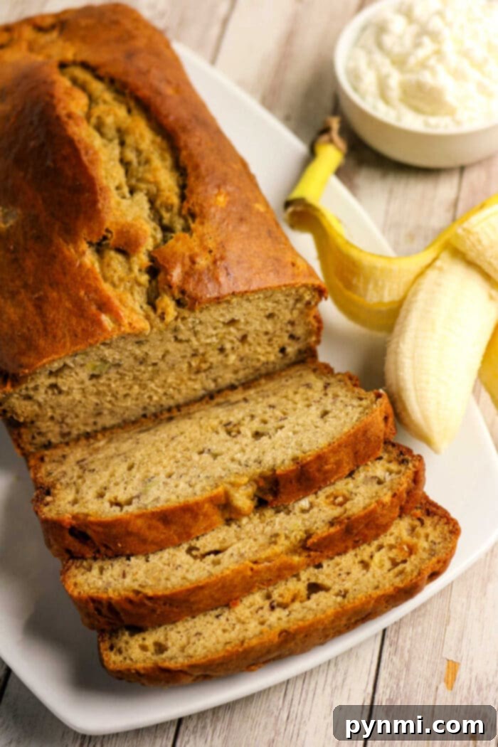Power-Packed Banana Bread 6 Sliced Protein Banana Bread on a plate with a peeled banana and a bowl of cottage cheese in the background.