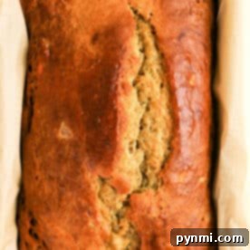 Golden brown loaf of Protein Banana Bread in a parchment-lined baking pan, viewed from above.
