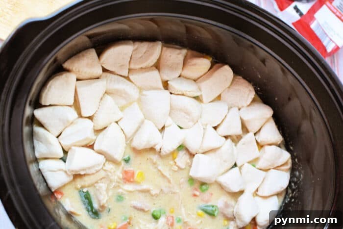 Slow-Cooker Chicken Pot Pie Casserole Recipe 6 Crockpot Chicken and vegetable stew in a slow cooker, topped with raw biscuit dough pieces arranged in a ring for a delicious twist on classic Chicken Pot Pie.