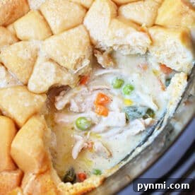 Slow-Cooker Chicken Pot Pie Casserole Recipe 8 Close-up of a creamy Chicken Pot Pie with vegetables and a golden-brown biscuit topping, partially served—comfort food made easy in the Crockpot.