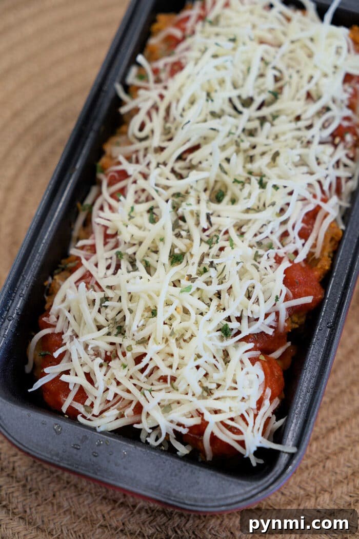 Chicken Parmesan Meatloaf Recipe: Savory Italian-Style Loaf 4 A loaf pan filled with Chicken Parmesan Meatloaf, topped with shredded cheese and herbs, ready to be baked.