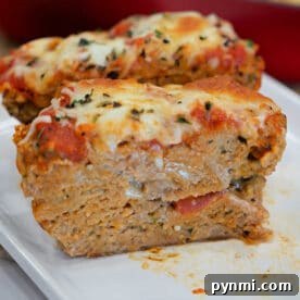 Chicken Parmesan Meatloaf Recipe: Savory Italian-Style Loaf 6 Two slices of cheesy, baked Chicken Parmesan Meatloaf topped with tomato sauce and herbs sit on a white plate.