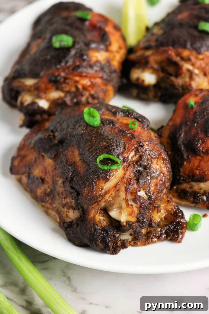 Oven-Baked Jerk Chicken Recipe – Crispy, Flavorful & Authentic 6 Four pieces of dark, grilled Jerk Chicken garnished with green onions, served on a white plate.