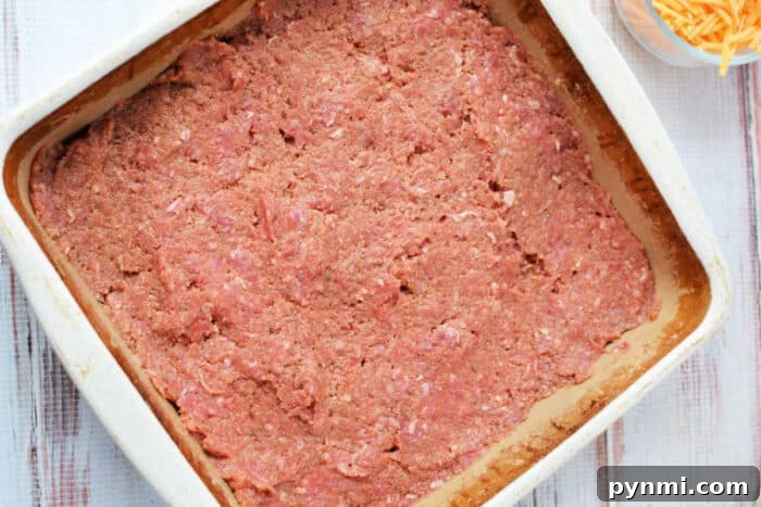 Mac and Cheese Meatloaf Casserole Recipe for Comfort Dinner 4 Raw ground meat mixture spread evenly in a square baking dish, ready to be cooked into a hearty meatloaf casserole.