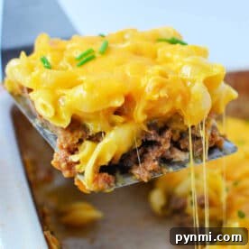 Mac and Cheese Meatloaf Casserole Recipe for Comfort Dinner 7 A spatula lifts a cheesy meatloaf casserole from a baking dish, topped with melted cheese and chives, blending classic casserole comfort with the creamy goodness of mac and cheese.