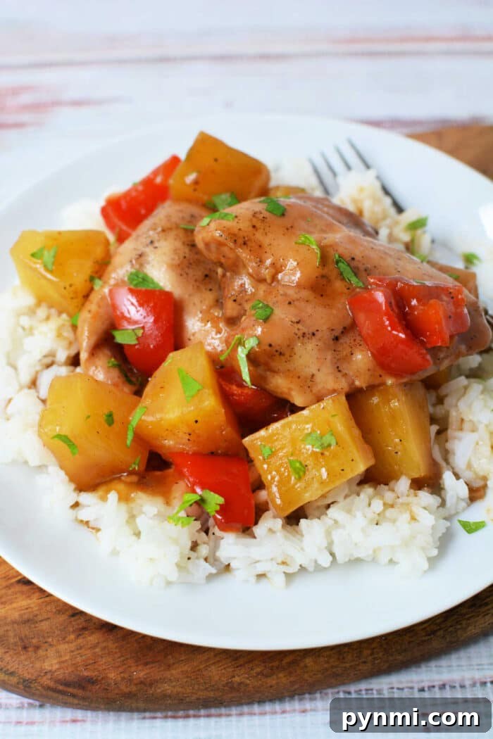Slow Cooker Pineapple Chicken: Tender, Juicy Crockpot Recipe 2 Slow Cooker Chicken with pineapple chunks and red bell peppers served over white rice on a white plate, finished with a splash of pineapple juice for extra flavor.