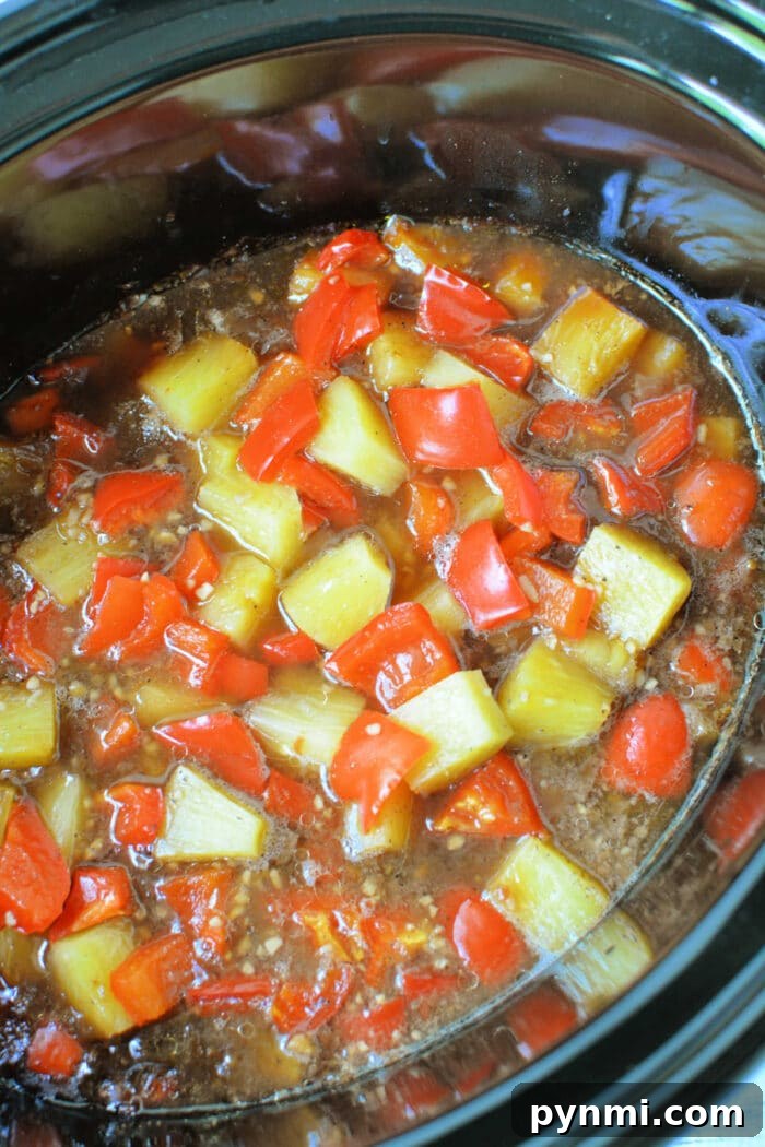 Slow Cooker Pineapple Chicken: Tender, Juicy Crockpot Recipe 5 Diced red bell peppers, pineapple chunks, and tender slow cooker chicken simmer in a rich brown sauce for an easy chicken recipe.