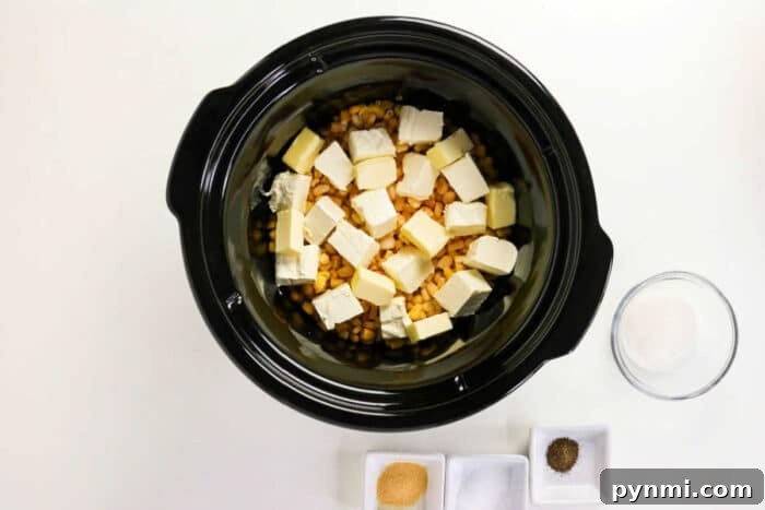 Slow Cooker Creamed Corn 4 Crockpot Creamed Corn with corn and butter cubes, with bowls of sugar, garlic powder, pepper, and salt nearby.