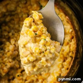 Slow Cooker Creamed Corn 7 A spoon scooping creamy Crockpot Creamed Corn casserole from a slow cooker.