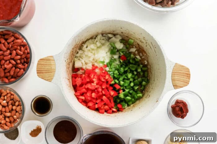 Diced onions, red bell peppers, and green bell peppers in a pot, surrounded by hearty chili ingredients—perfect for a delicious chuck roast chili or classic beef chili.